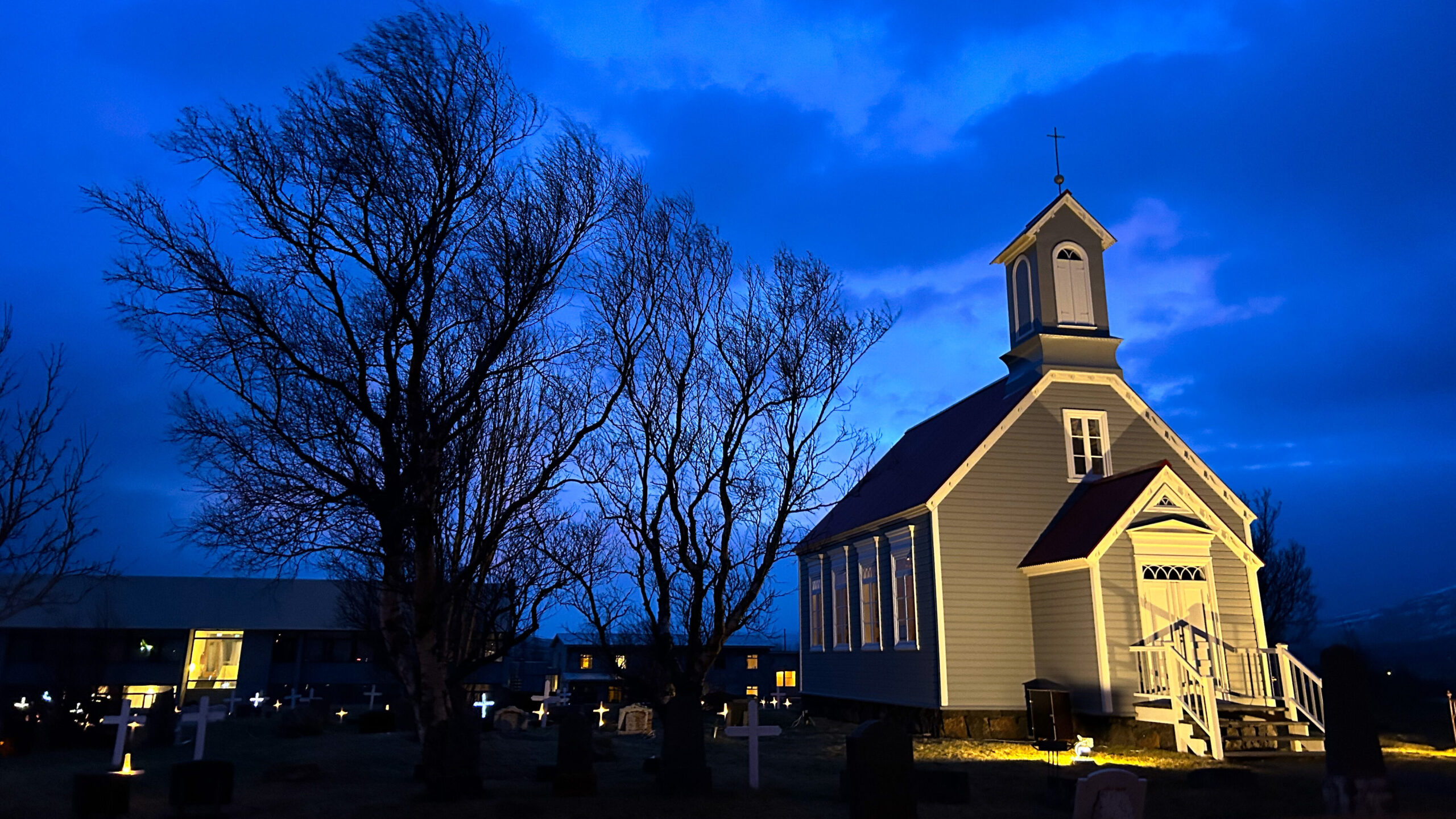 Die kleine Reykholtskirkja, eine aus Holz errichtete grau-weiße Kirche in Reykholt, Island. 