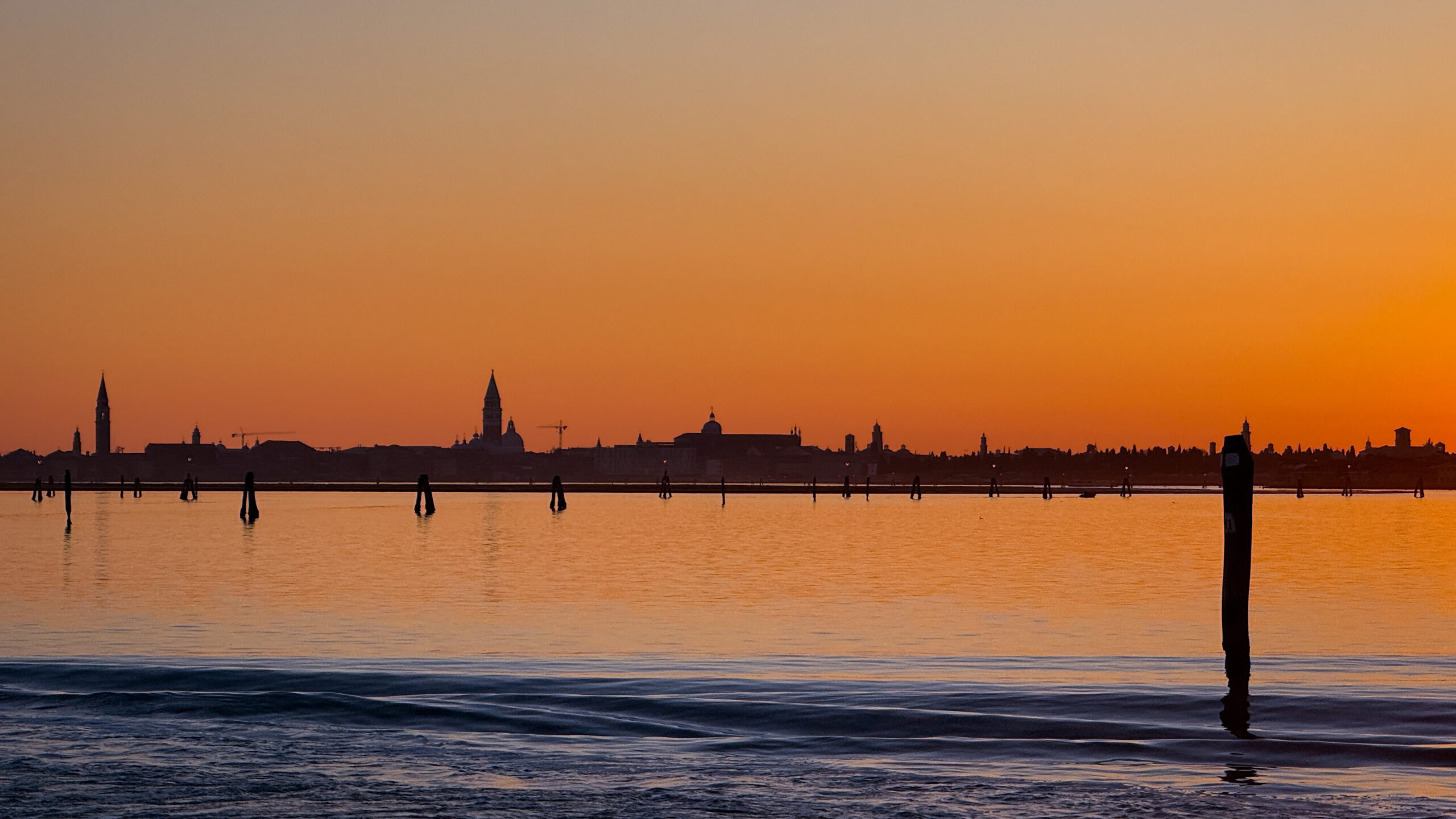 Sonnenuntergang über Venedig, rot-orangener Himmel, die Silhouette der Stadt im Hintergrund