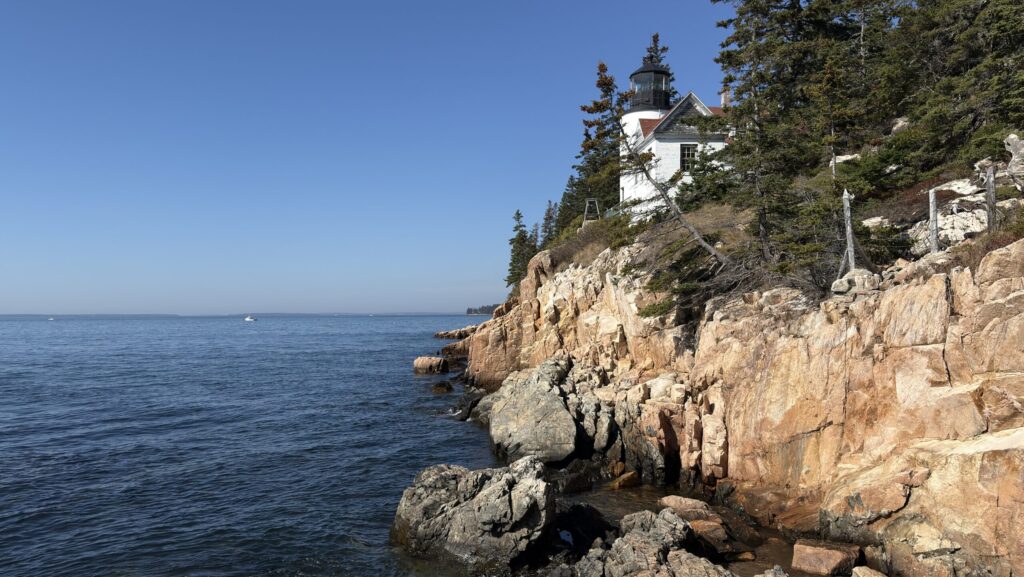 Leuchtturm auf steiler Klippe, im Vordergrund der Atlantik. 