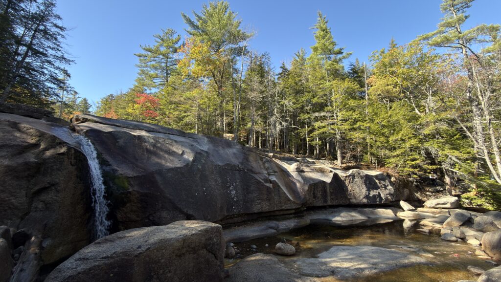Wasserfall vor Granitfelsen und bunten Laubbäumen
